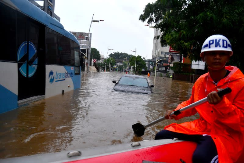 A security guard uses an inflatable boat as floods hit Kemang area in Jakarta
