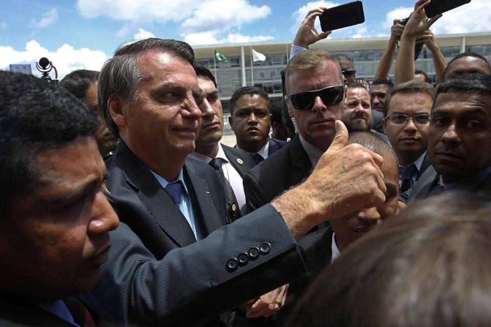 Brazil's President Jair Bolsonaro flashes a thumbs up as he greets supporters after attending a Changing of the Guard at the Planalto Presidential Palace, in Brasilia, Brazil, Thursday, Nov. 28, 2019. (AP Photo/Eraldo Peres)