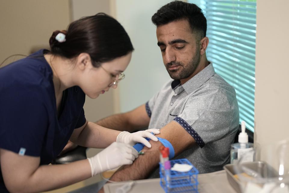 Abdul Wasi Safi, right, has his blood drawn by Bianca Gonzalez during a clinic visit, Wednesday, April 26, 2023, in Houston. Safi's days since his release from a Texas immigration detention center have been filled with medical appointments while living in Houston with his brother. (AP Photo/David J. Phillip)