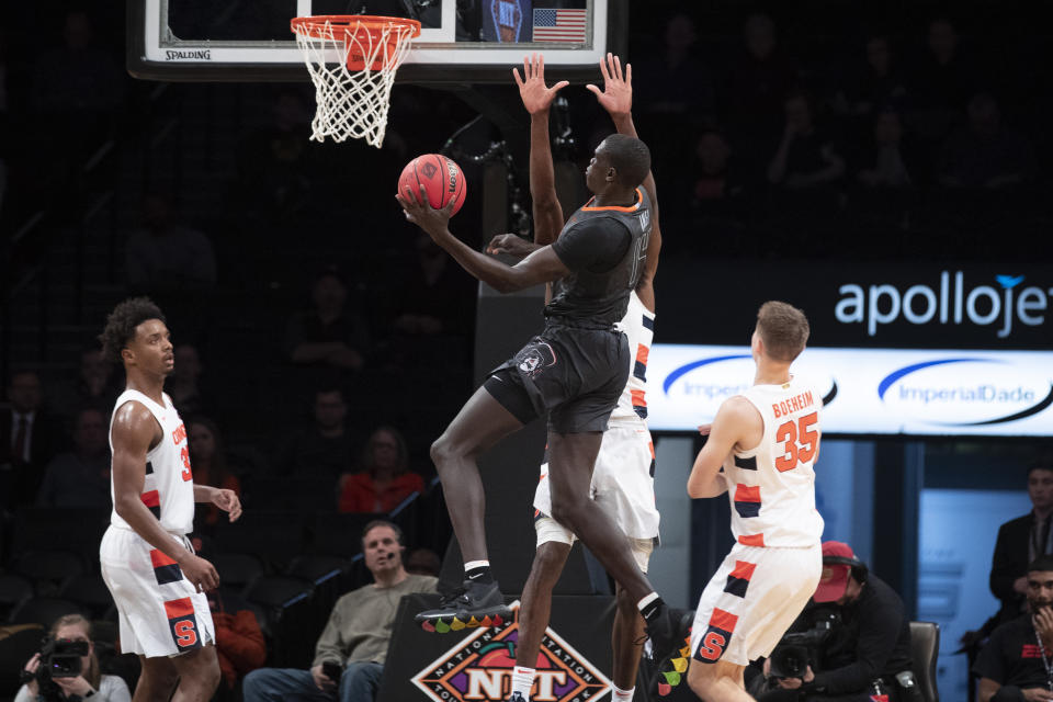 Oklahoma State forward Yor Anei (14) goes to the basket past Syracuse forward Elijah Hughes (33) and guard Buddy Boeheim (35) during the second half of an NCAA college semi final basketball game in the NIT Season Tip-Off tournament, Wednesday, Nov. 27, 2019, in New York. Oklahoma State won 86-72. (AP Photo/Mary Altaffer)