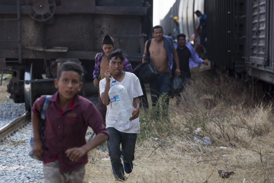 Central American migrants run for a parked train during their journey toward the US-Mexico border, in Ixtepec, Oaxaca state, Mexico, Tuesday, April 23, 2019. The once large caravan of about 3,000 people was essentially broken up by an immigration raid on Monday, as migrants fled into the hills, took refuge at shelters and churches or hopped passing freight trains. (AP Photo/Moises Castillo)