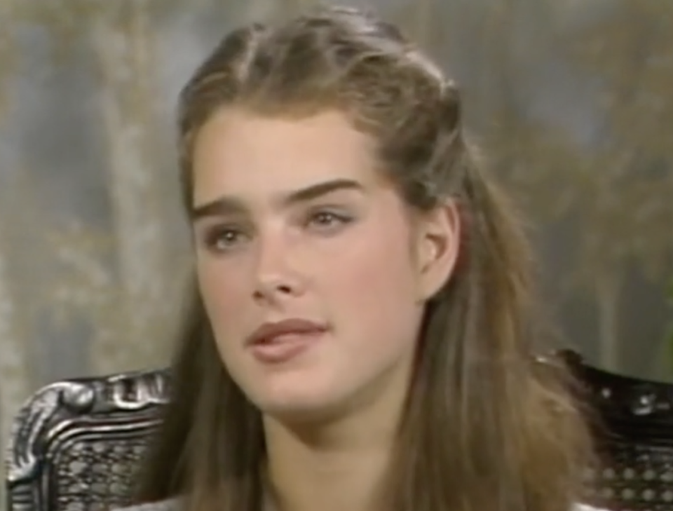 Close-up of Brooke Shields in an interview. She has long hair and wears a top with metallic embellishments