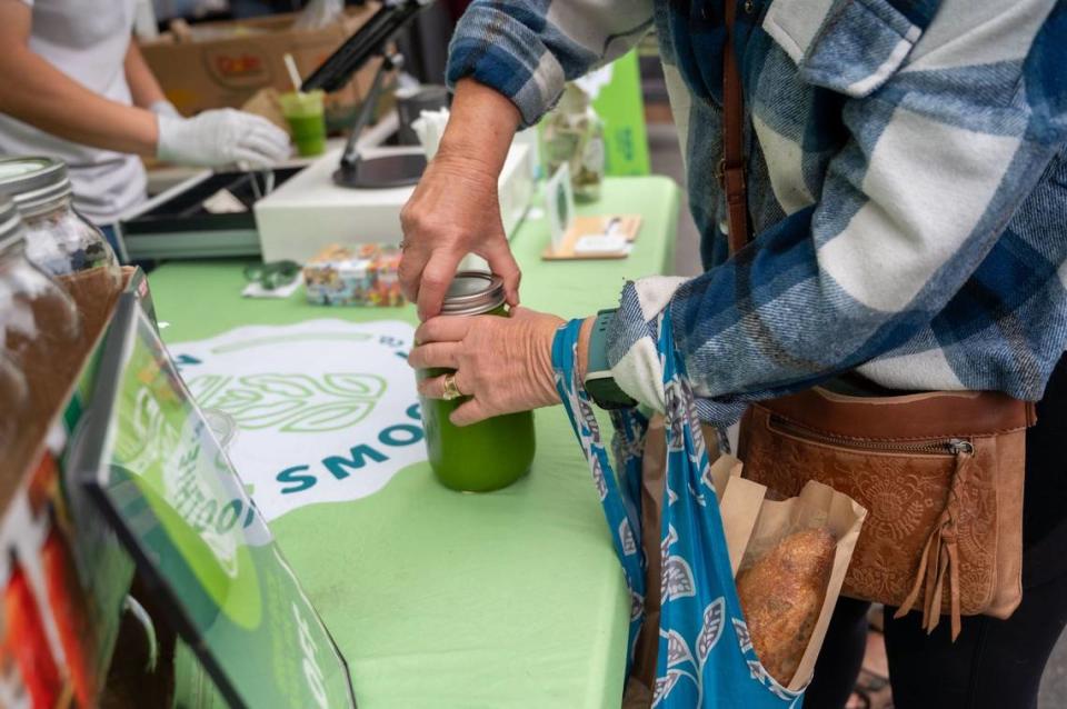 Returning customer Terry Luedtke purchases smoothie refill from Green Smoothie Co. at the Midtown Farmers Market in Sacramento on Saturday, July 27, 2024.