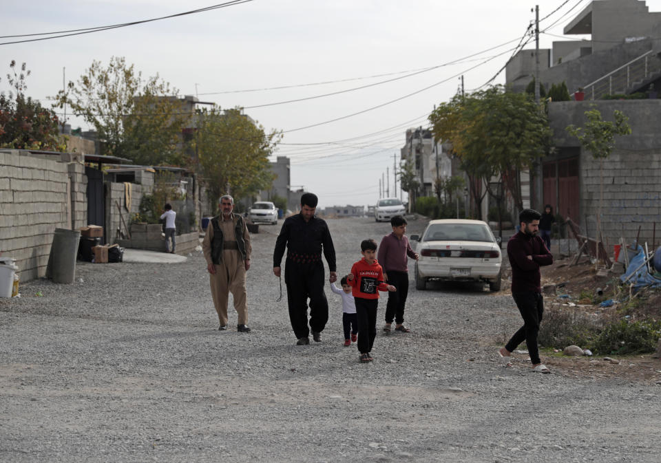 Zana Mamand, second left, the brother of Twana Mamand who was lost at sea in the English Channel trying to get to Britain, walks with family members, outside their house in Ranya, Iraq, Tuesday, Nov. 30, 2021. Twana had tried and failed five times to cross the English Channel from Calais before he boarded a small boat on the evening of Nov. 23. (AP Photo/Khalid Mohammed)