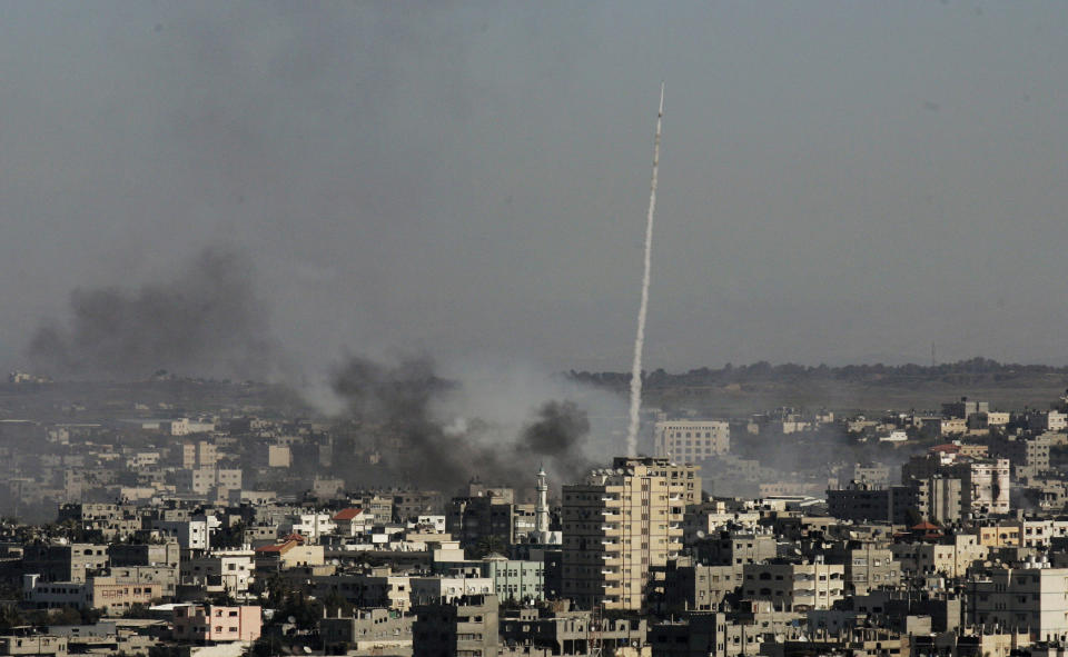 FILE - In this Tuesday, Jan. 6, 2009 file photo, a rocket fired by Palestinian militants at southern Israel leaves a thin trail of white smoke, as smoke caused by explosions from Israeli forces' operations rises from buildings on the outskirts of Gaza City. A leader of one of Gaza's secretive jihadi groups says the al-Qaida-inspired movement now has several thousand armed fighters in the seaside strip, posing a formidable threat to both Israel and the area's Hamas rulers. (AP Photos/Hatem Moussa, File)