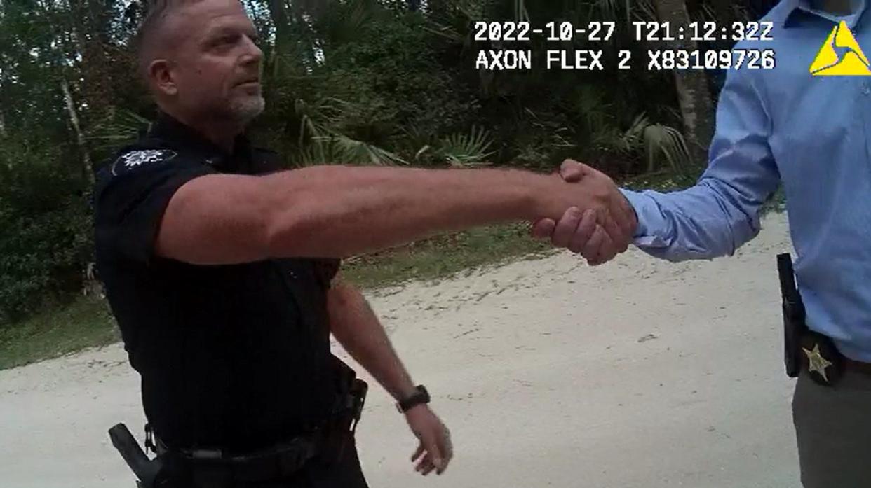 Lt. Michael Schoenbrod of the Daytona Beach Shores Public Safety Department greets two Volusia County Sheriff's Office officials and a Division of Children and Families caseworker outside his home on Oct. 27, 2022, about three weeks after he said he put a 3 1/2-year-old child in a jail holding cell, handcuffed, for a potty-training lesson.