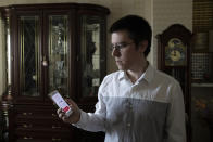 In this Wednesday, May 27, 2020, photo, Vladimir Perevalov shows a Social Monitoring app installed on his phone in his apartment in Shcherbinka, outside Moscow, Russia. A smartphone app designed to track Moscow's quarantined coronavirus patients was rolled out by city officials in early April, but complaints about it have mushroomed. Perevalov, who installed the app and diligently took selfies, was fined three times for $168. (AP Photo/Pavel Golovkin)