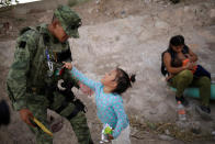 Un miembro de la Guardia Nacional de México juega en Ciudad Juárez con una niña hondureña después de que haya sido detenida junto a su madre y su hermana cuando intentaban cruzar ilegalmente a El Paso (Estados Unidos) el 26 de junio. (Foto: Jose Luis Gonzalez / Reuters).