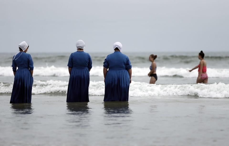 Rosa Graber, third from left, Margerie Steury, second left, and Joanne Steury, left, look out to sea as they touch Pacific Ocean waters for the first time during a family trip from their Amish community in Michigan, on June 9, 2016, in Coronado, Colorado.