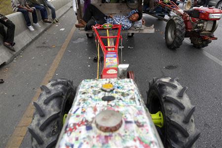 Rice farmers rest by their tractors on a main highway where they spent a night in Ayutthaya province February 21, 2014. REUTERS/Damir Sagolj