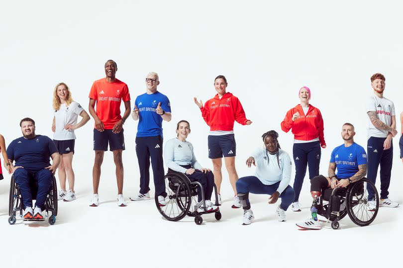 17 people standing in a line and all posing for the camera. There are a number of people in wheelchairs and with prosthetics.