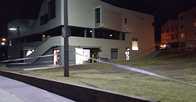 Police tape runs across the front of a building in Bondi Beach.