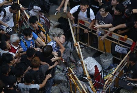 People try to prevent a man from removing a barricade set up by pro-democracy protesters blocking a main road at Hong Kong's shopping Mongkok district October 4, 2014. REUTERS/Bobby Yip