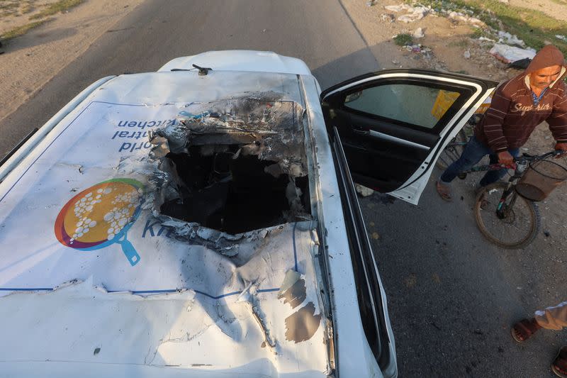 Un palestino pasa en bicicleta junto a un vehículo averiado donde los empleados de World Central Kitchen (WCK), incluidos extranjeros, murieron en un ataque aéreo israelí, en medio del conflicto en curso entre Israel y Hamás, en Deir Al-Balah, en el centro de la Franja de Gaza