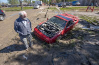 Tim Evans, owner of Fieros Forever, inspects the damage to his Lamborghini Diablo kit car that lay in a muddy ditch near downtown Sanford, Mich., Thursday, May 21, 2020. Evans lost several vehicles due to flooding that occurred after the Sanford dam failed earlier in the week. (David Guralnick/Detroit News via AP)