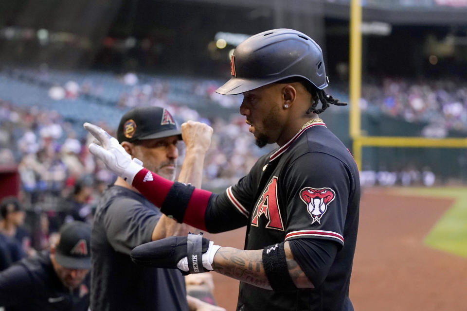 Arizona Diamondbacks' Ketel Marte, right, returns to the dugout and congratulations from manager Torey Lovullo, left, after Marte scored against the Colorado Rockies during the first inning of a baseball game Wednesday, May 31, 2023, in Phoenix. (AP Photo/Ross D. Franklin)