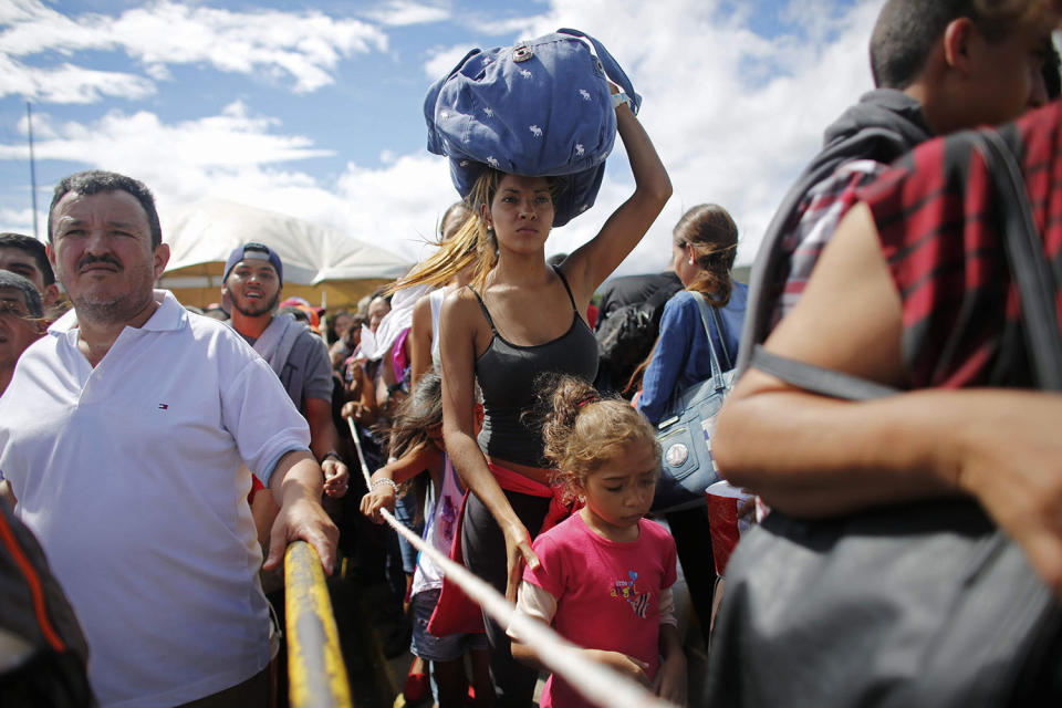 FILE - A woman carrying a bundle on her head waits in line to cross the border on the Simon Bolivar bridge to enter Colombia to hunt for food and medicine, in San Antonio del Tachira, Venezuela, July 17, 2016. Over the last 10 years, more than 7.1 million people have left Venezuela amid a political, economic and humanitarian crisis that has marked the entirety of President Nicolas Maduro’s government. (AP Photo/Ariana Cubillos, File)