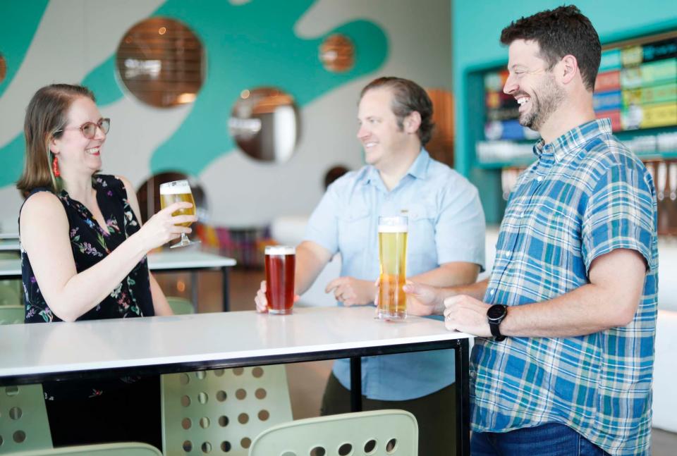 Chief Operating Officer Amanda Thompson, from left, co-owner Davin Bartosch and co-owner Kellan Bartosch enjoy their drinks inside WISEACRE HQ, at 398 S. B.B. King Blvd., on Aug. 18, 2023. The Memphis craft brewery, which has two locations, is celebrating 10 years in business.