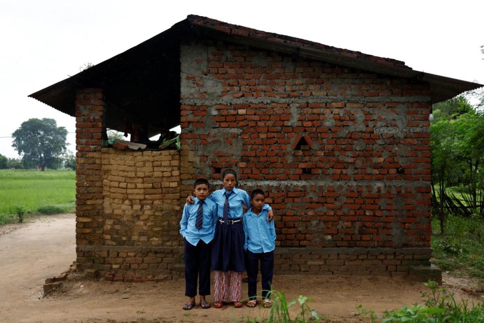 Parwati and her sons, Resham and Arjun, pose outside their house in Punarbas (Reuters)