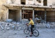 A boy sits on a bicycle in front of damaged shops after an airstrike on the rebel held al-Qaterji neighbourhood of Aleppo, Syria September 25, 2016. REUTERS/Abdalrhman Ismail
