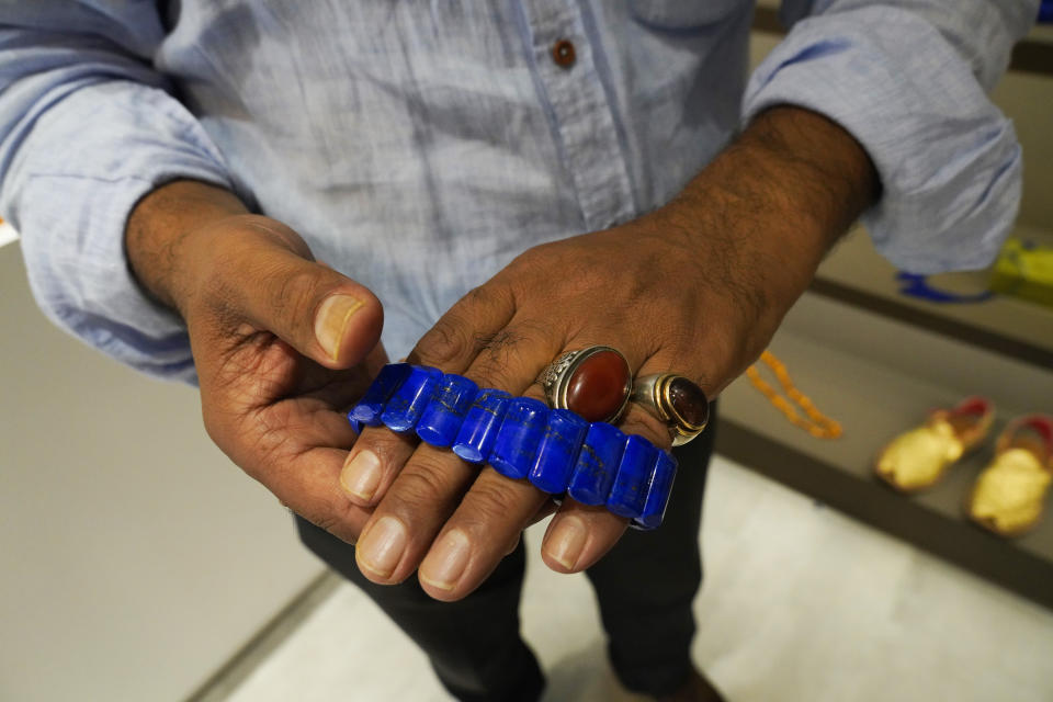 Mohammed Omer Rahimy shows off jewelry for sale at the Afghanistan pavilion at Expo 2020 in Dubai, United Arab Emirates, Thursday, Oct. 7, 2021. Rahimy has opened the Afghanistan pavilion at Expo 2020 about a week after the world's fair began without it amid the turmoil facing his country following the Taliban takeover there. (AP Photo/Jon Gambrell)