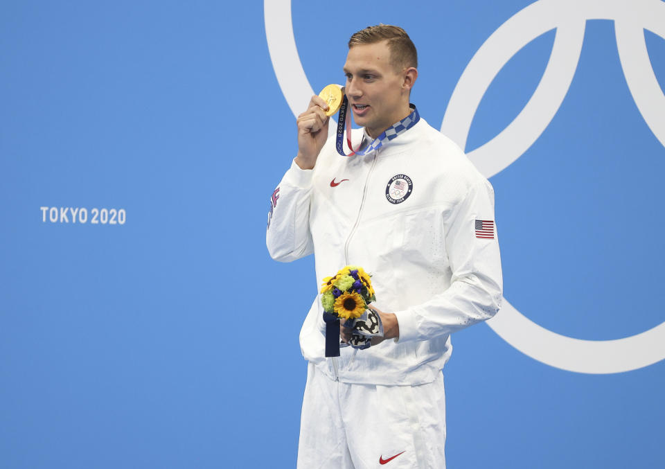 Caeleb Dressel holding up his gold medal during the medal ceremony of the Men's 50m Freestyle Final