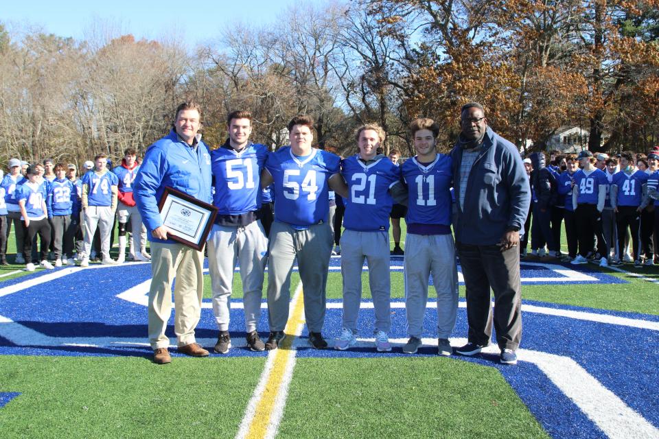 Scituate High football coach Herb Devine, left, poses with his captains -- No. 51 Jack Thompson, No. 54 Michael Sheskey, No. 21 Keegan Sullivan and No. 11 Andrew Bossey -- and New England Patriots Hall of Fame linebacker Andre Tippett, right, at the school on Tuesday, Nov. 16, 2021. Devine was selected as the New England Patriots High School Coach of the Week for the Sailors' 21-14 win over Ashland in the Div. 4 state quarterfinals.