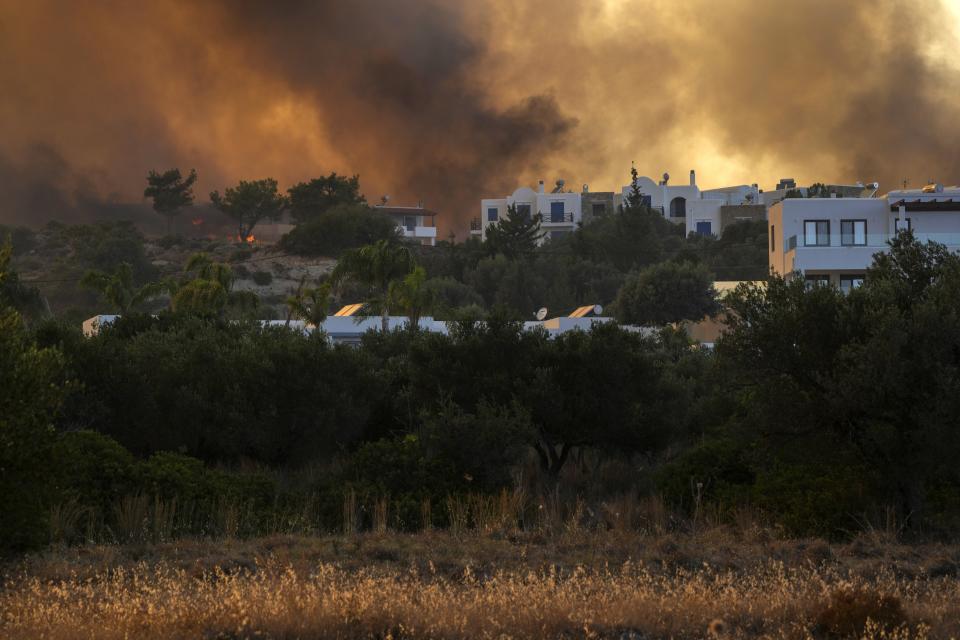 A wildfire burns in Gennadi village, on the Aegean Sea island of Rhodes, southeastern Greece, on Tuesday, July 25, 2023. A firefighting plane has crashed in southern Greece, killing both crew members, as authorities are battling fires across the country amid a return of heat wave temperatures. (AP Photo/Petros Giannakouris)