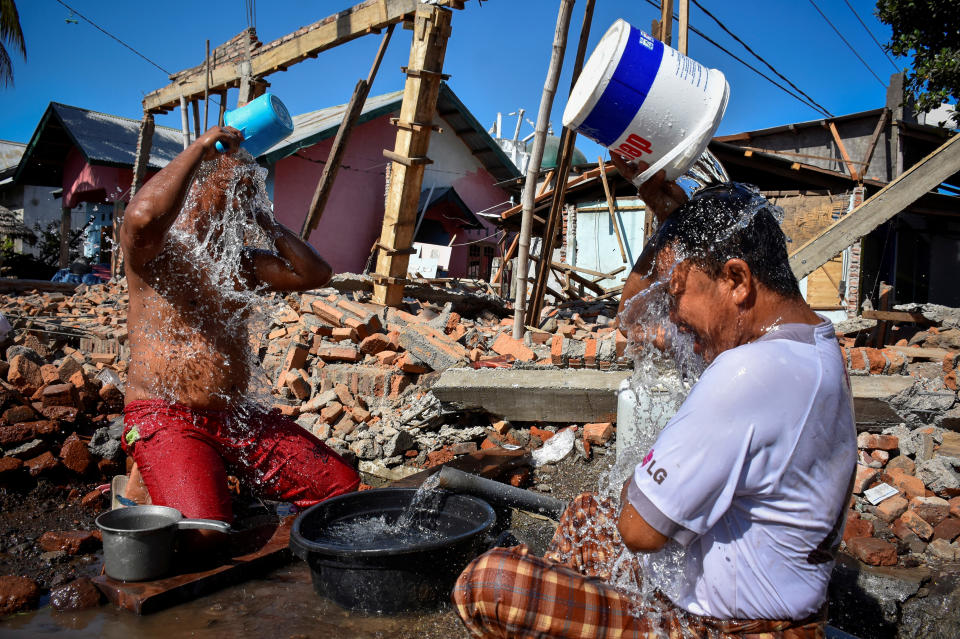 <p>Two men bathe near their homes damaged or destroyed by an earthquake in Kayangan District, Lombok, Indonesia, Aug. 10, 2018. (Photo: Antara Foto/Ahmad Subaid via Reuters) </p>