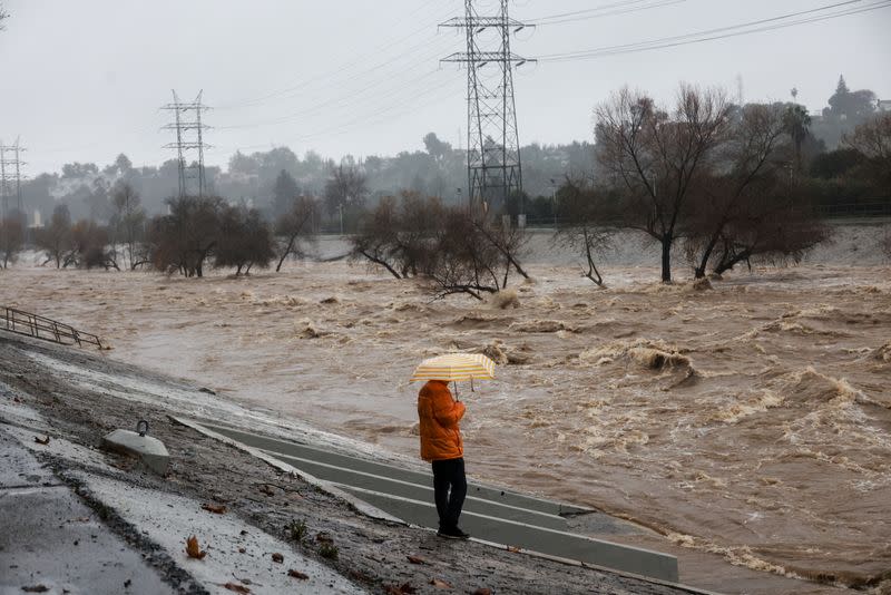 FOTO DE ARCHIVO. Una persona con un paraguas en la mano observa el río de Los Ángeles durante las fuertes lluvias en Los Ángeles, California, EEUU