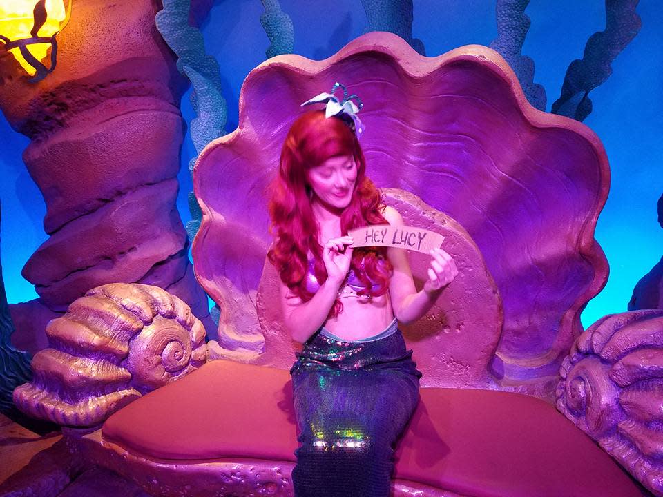 Ariel the mermaid sits in her Disney World's Magic Kingdom lagoon, holding a sign for a fan, who is not Neil Patrick Harris.