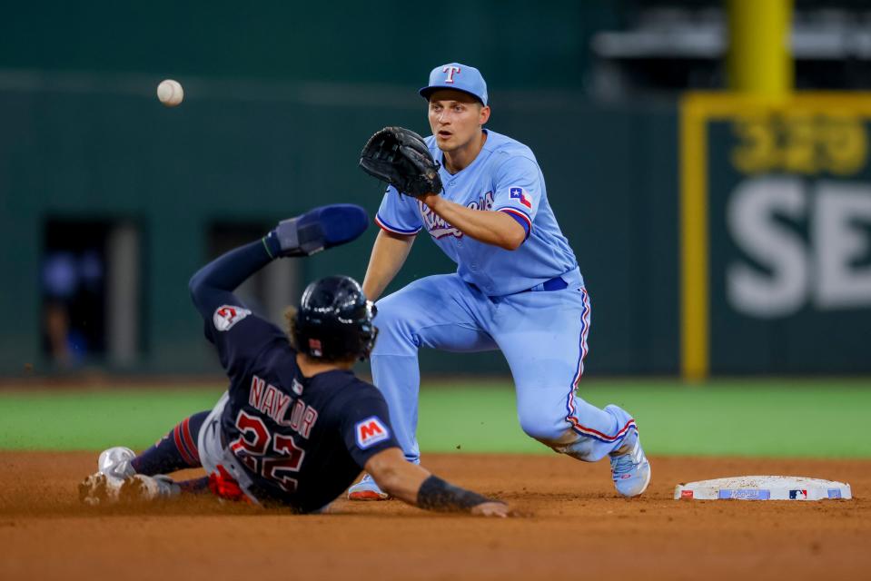 Texas Rangers' Corey Seager, right, completes a double play by tagging Cleveland Guardians' Josh Naylor, left, to end the fifth inning of a baseball game, Sunday, July 16, 2023, in Arlington, Texas. (AP Photo/Gareth Patterson)