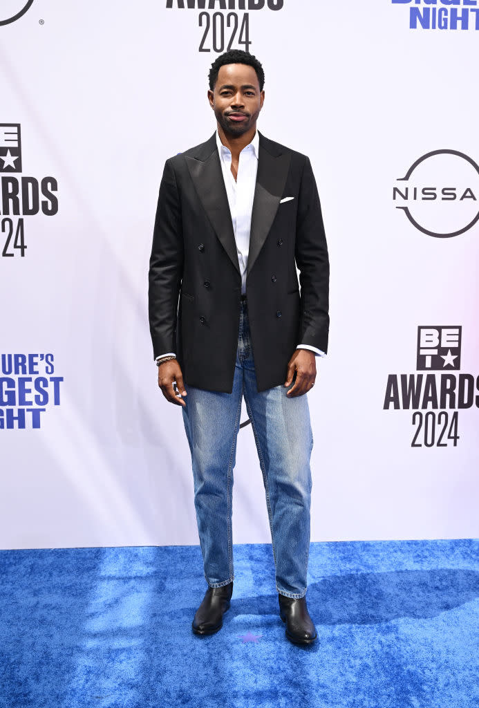 Jay Ellis at the BET Awards 2024, wearing a black blazer, white shirt, and blue jeans on the blue carpet