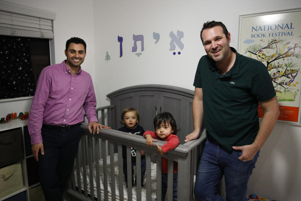 FILE - In the Tuesday, Jan. 23, 2018 file photo, Elad Dvash-Banks, left, and his partner, Andrew, pose for photos with their twin sons, Ethan, center right, and Aiden in their apartment in Los Angeles. A federal judge in California has ruled that a twin son of the gay couple has been an American citizen since birth, handing a defeat to the U.S. government, which had only granted the status to his brother. District Judge John Walter said Thursday, Feb. 21, 2019, that the State Department was wrong to deny citizenship to 2-year-old Ethan Dvash-Banks. (AP Photo/Jae C. Hong, File)