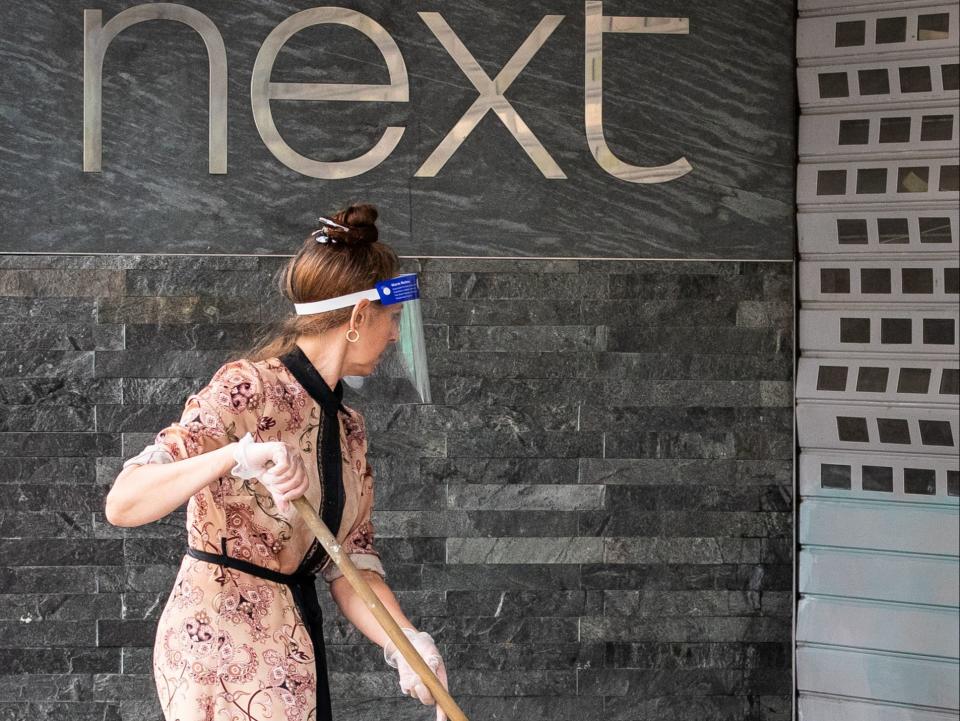 A shop worker cleans the exterior of a Next retail shop on Oxford Street (PA)