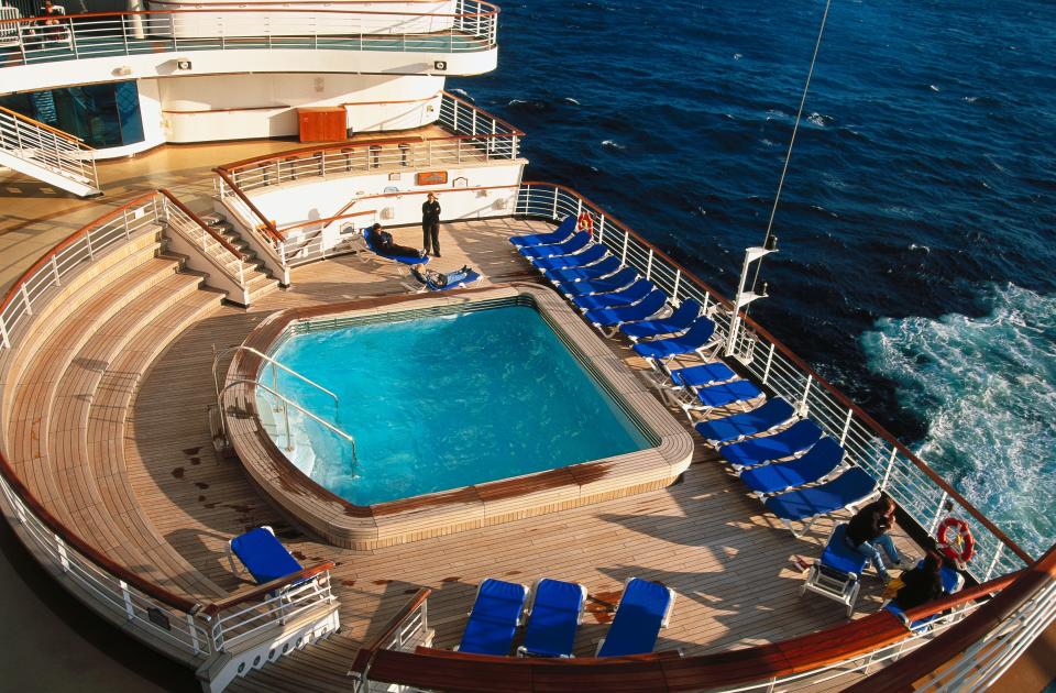 a pool surrounded by empty lounge chairs on a cruise