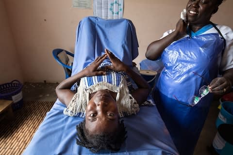 Midwife Sheilla with Ashitotu, a mother of five who was widowed and then left by her second husband - Credit: Simon Townsley/The Telegraph