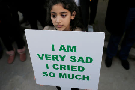 A girl holds a sign in front of Denmark's embassy in Rabat to honour Maren Ueland from Norway and Louisa Vesterager Jespersen from Denmark, who were killed in Morocco, in Rabat, Morocco December 22, 2018. REUTERS/Youssef Boudlal