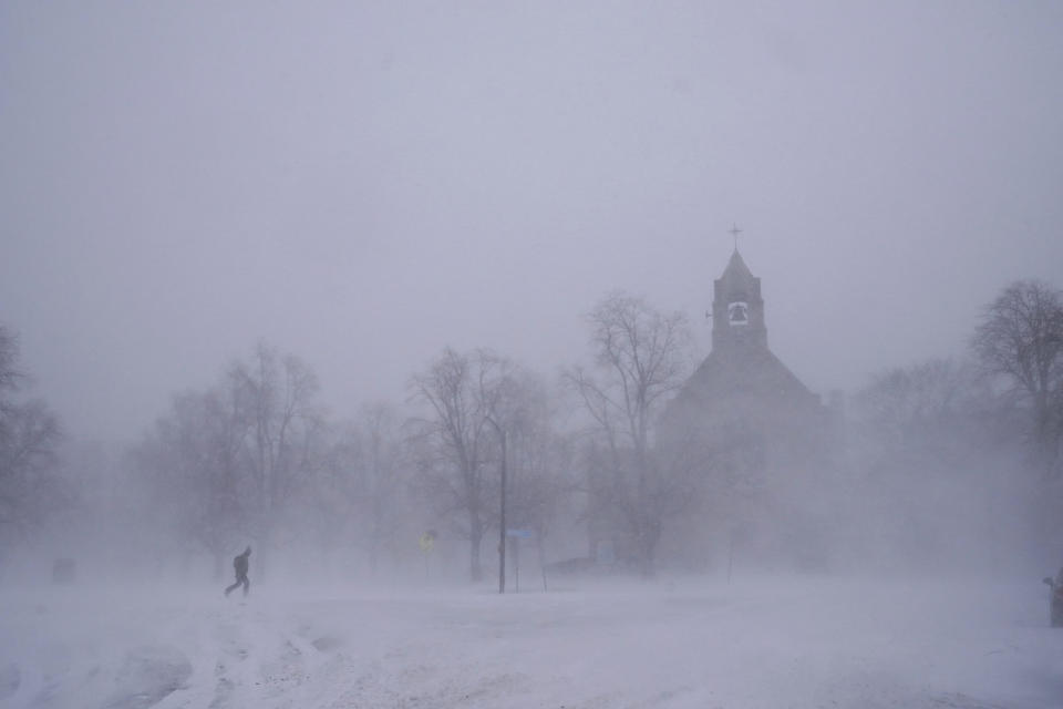 Un peatón con equipo para la nieve avanza por el Colonial Circle, con la silueta de la iglesia episcopaliana de St. John's Grace entre la ventisca, en Buffalo, Nueva York, el sábado 24 de diciembre de 2022. (Derek Gee/The Buffalo News via AP)