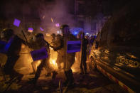 Policemen in riot gear move past a burning barricade during clashes with protestors in Barcelona, Spain, Tuesday, Oct. 15, 2019. Spain's Supreme Court on Monday convicted 12 former Catalan politicians and activists for their roles in a secession bid in 2017, a ruling that immediately inflamed independence supporters in the wealthy northeastern region. (AP Photo/Emilio Morenatti)