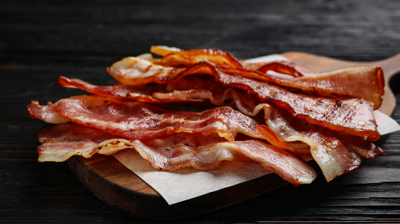 Crispy bacon strips on wooden board