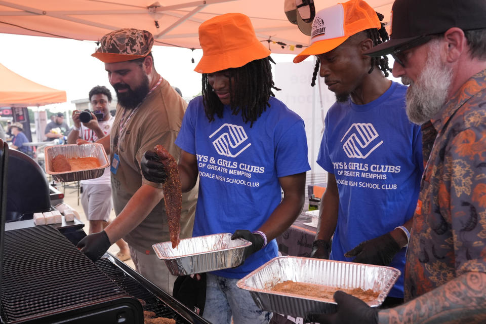 Boys and Girls Club members Meech Snow, second from left, and Joseph Woody, second from right, cook with Sam Temple, far left, and Justin Bilbao, far right, of Traeger Grills at the World Championship Barbecue Cooking Contest, Friday, May 17, 2024, in Memphis, Tenn. (AP Photo/George Walker IV)