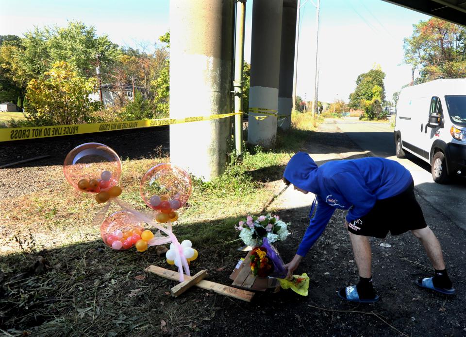 A member of the Pearl River High School football team lays flowers at the site of a crash that killed  Altin Nezaj, a Port Chester High School senior and football player, as they spoke outside school Oct.15, 2019. Nezaj was one of two people who died in the fiery crash that took place Sunday afternoon. 