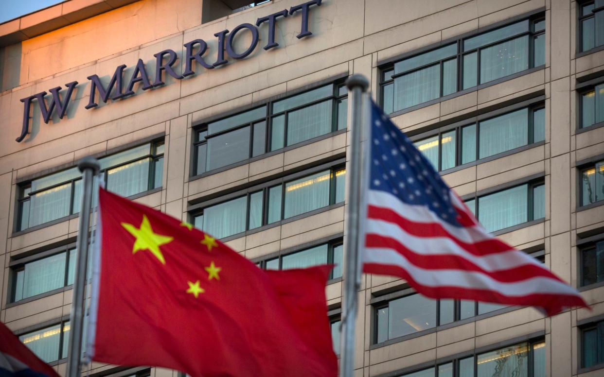 Chinese and American flags fly outside of a JW Marriott hotel in Beijing - AP