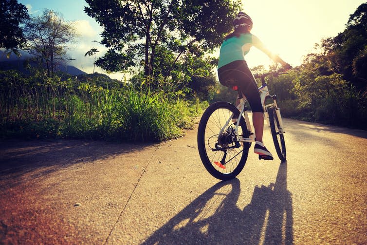 Female cyclist cycling on sunrise forest trail