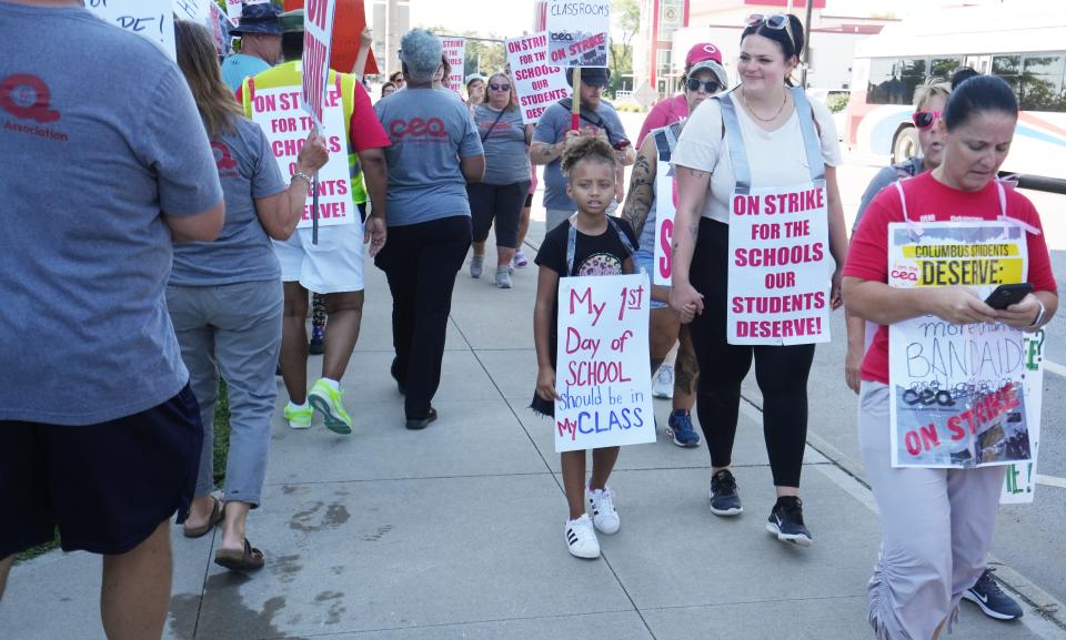 As the Columbus City Schools teacher strike moves into the third day, kindergarten teacher Bethany Angel holds the hand of former student Zaniah Davison. Angel works at Siebert Elementary School; Davison is now a second-grader there They were marching on the picket line at Downtown Columbus High School.