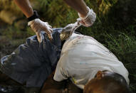 FILE - Police take out a bag of Marijuana from the pocket of one of two unidentified alleged drug suspects after they were shot dead by police as they tried to evade a checkpoint in Quezon city, north of Manila, Philippines on Sept. 6, 2016. More than 6,250 mostly poor drug suspects have been killed in Duterte's crackdown based on a government count since he expanded the campaign nationwide after becoming president in 2016. (AP Photo/Aaron Favila, File)