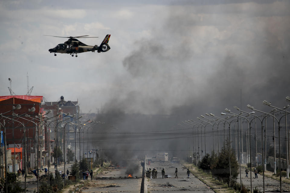 An Army helicopter flies over the road leading to the state-own Senkata filling gas plant in El Alto, on the outskirts of La Paz, Bolivia, as supporters of former President Evo Morales set up barricades, Tuesday, Nov. 19, 2019. Morales' backers have taken to the streets asking for his return since he resigned on Nov. 10 under pressure from the military after weeks of protests against him over a disputed election he claim to have won. (AP Photo/Natacha Pisarenko)