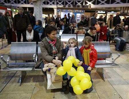 Iveta Lacey-Holborn and her daughters Esther, age three and Sofia, age five, wait for their train at Paddington station in central London December 23, 2013. REUTERS/Olivia Harris