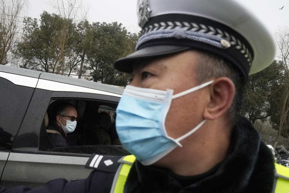 Peter Ben Embarek of the World Health Organization team passes by a Chinese police officer as he leaves in a convoy from the Baishazhou wholesale market on the third day of field visit in Wuhan in central China's Hubei province on Sunday, Jan. 31, 2021. (AP Photo/Ng Han Guan)